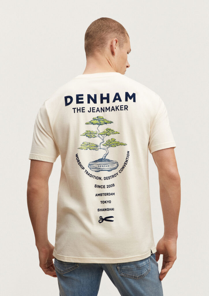 A back shot of a man modelling a Denham shirt. The illustration features a bonsai surrounded by typography.