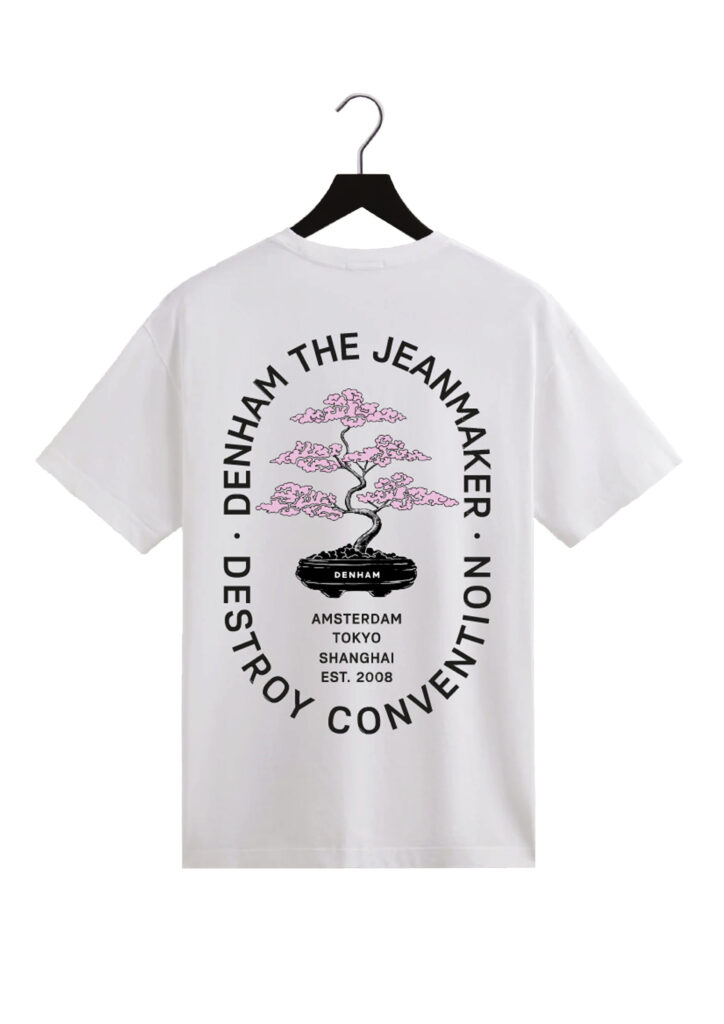 A t-shirt with an illustration of a bonsai with pink blossom. Typography surrounds it.